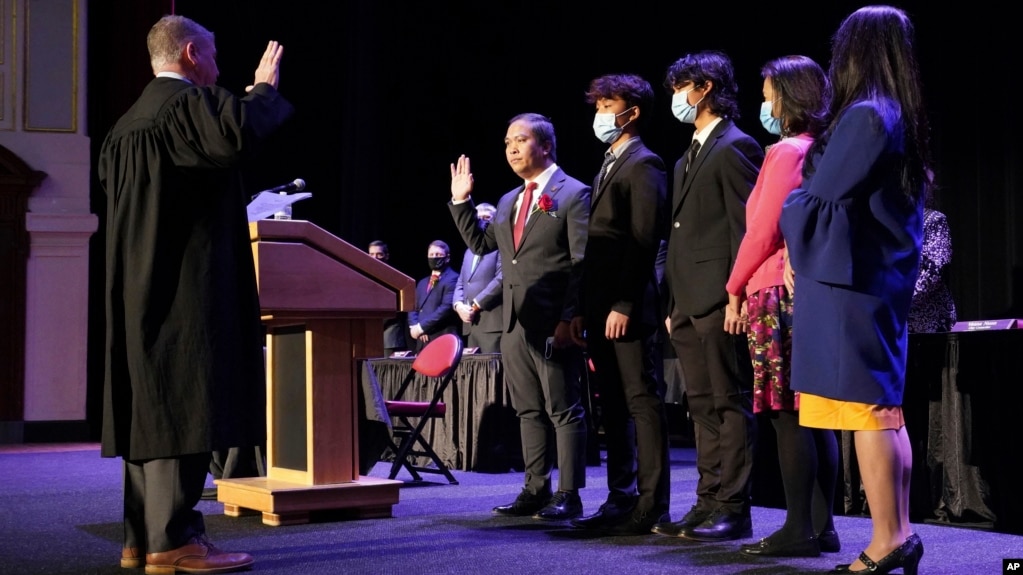 In this photo provided by Peg Shanahan, Lowell District Court Judge Stephen Geary, left, swears in new Mayor Sokhary Chau during the Lowell City Council swearing-in ceremony, Monday, Jan. 3, 2022, in Lowell, Massachusetts. (Peg Shanahan via AP)