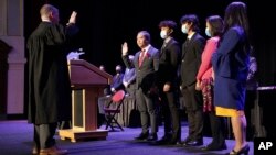 In this photo provided by Peg Shanahan, Lowell District Court Judge Stephen Geary, left, swears in new Mayor Sokhary Chau during the Lowell City Council swearing-in ceremony, Monday, Jan. 3, 2022, in Lowell, Massachusetts. (Peg Shanahan via AP)