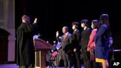 In this photo provided by Peg Shanahan, Lowell District Court Judge Stephen Geary, left, swears in new Mayor Sokhary Chau during the Lowell City Council swearing-in ceremony, Monday, Jan. 3, 2022, in Lowell, Massachusetts. (Peg Shanahan via AP)