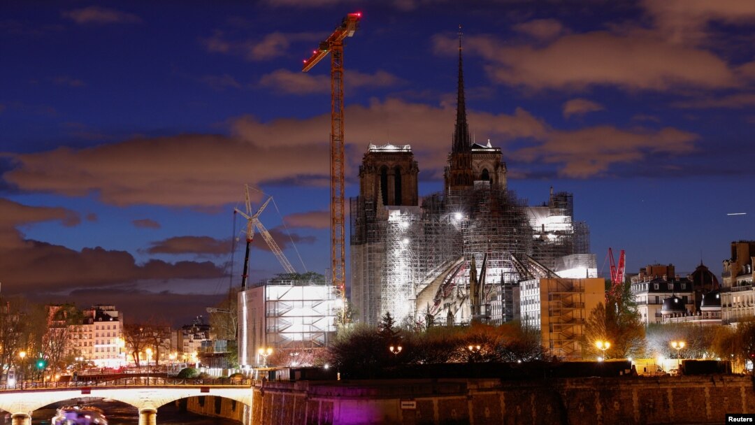 Una vista nocturna muestra la Catedral de Notre-Dame de París, que fue devastada por un incendio en 2019, con una nueva aguja, coronada por el gallo y la cruz, mientras continúan los trabajos de restauración en París, Francia, el 30 de marzo de 2024.