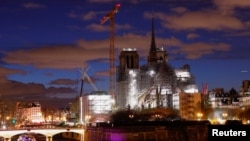 Una vista nocturna muestra la Catedral de Notre-Dame de París, que fue devastada por un incendio en 2019, con una nueva aguja, coronada por el gallo y la cruz, mientras continúan los trabajos de restauración en París, Francia, el 30 de marzo de 2024.