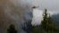 A firefighting helicopter makes a water drop as wildfire burns at the village of Ippokratios Politia, north of Athens, Greece August 6, 2021.
