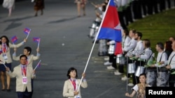 FILE - Cambodian flag-bearer Davin Sorn leads her nation's contingent in the athletes parade during the opening ceremonies of the London 2012 Olympic Games at Olympic Stadium, July 27, 2012. 