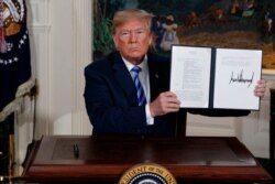 FILE - U.S. President Donald Trump shows a signed memorandum after delivering a statement on the Iran nuclear deal from the Diplomatic Reception Room of the White House, May 8, 2018.