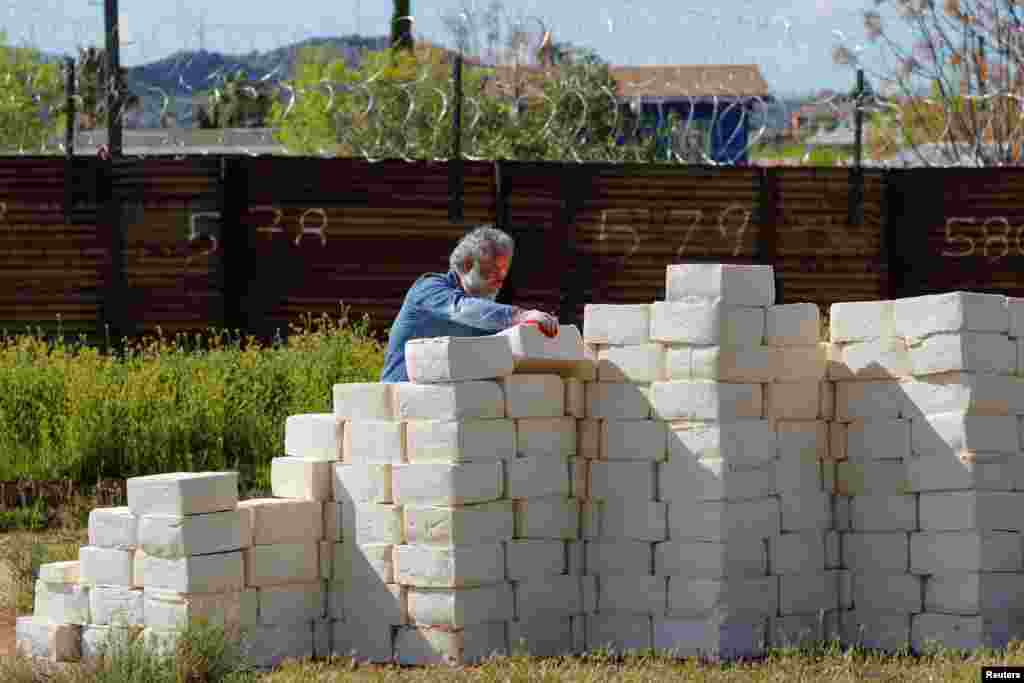 Canadian-born artist Cosimo Cavallaro builds a wall made of cheese as he crowdfunds his project next to a portion of the U.S.-Mexico border wall near Tecate, California, U.S., March 28, 2019.