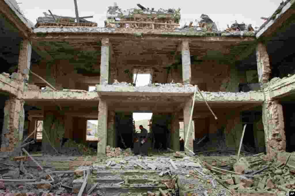 April 14: An Afghan police official investigates a damaged building at the scene of a suicide car bomb explosion on the outskirts of Kabul, Afghanistan. (AP)