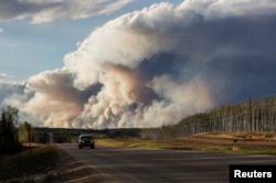 Smoke billows from the Fort McMurray wildfires as a truck drives down the highway in Kinosis, Alberta, Canada, May 5, 2016.