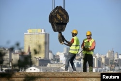 FILE - Construction workers build a bridge against the skyline of Mozambique's capital, Maputo, April 15, 2016.