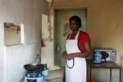 Regina Anyango, owner of small food kiosk in Nairobi, uses ethanol fuel to prepare meals for customers. Her kitchen is free of fumes and smoke from charcoal use. (Mohammed Yusuf/VOA)