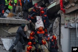Petugas penyelamat Turki membawa Ergin Guzeloglan, 36, ke ambulans setelah menariknya keluar dari bangunan yang runtuh lima hari setelah gempa, di Hatay, Turki selatan, Sabtu dini hari, 11 Februari 2023. (Foto: AP)