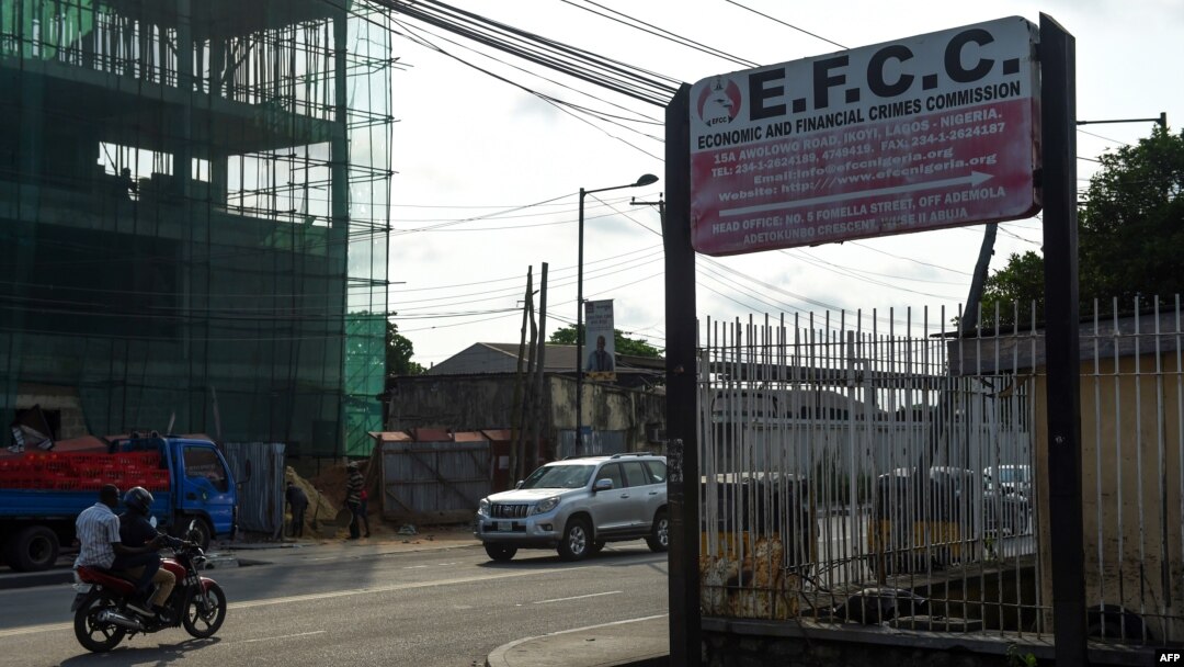 FILE - A motorcycle taxi drives past the sign of the Economic and Financial Crimes Commission (EFCC) in Lagos, Nigeria, Oct. 3, 2016.