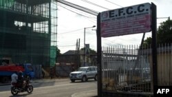 FILE - A motorcycle taxi drives past the sign of the Economic and Financial Crimes Commission (EFCC) in Lagos, Nigeria, Oct. 3, 2016.