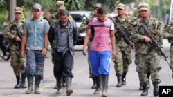 FILE - Soldiers escort three suspected rebels of the Revolutionary Armed Forces of Colombia (FARC) who allegedly surrendered to the army, in Medellin, Colombia, September 20, 2012. 