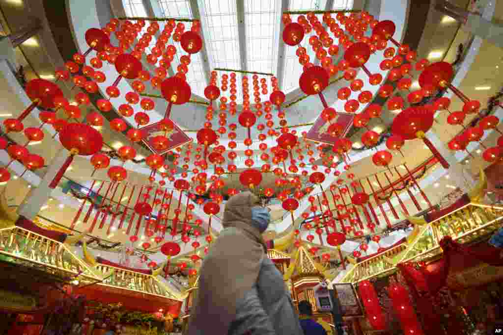 A woman walks under Chinese Lunar New Year decoration at a shopping mall in Kuala Lumpur, Malaysia.