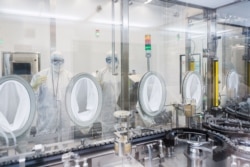 Lab technicians fill vials of investigational coronavirus disease (COVID-19) treatment drug remdesivir at a Gilead Sciences facility in La Verne, California, U.S. March 18, 2020.