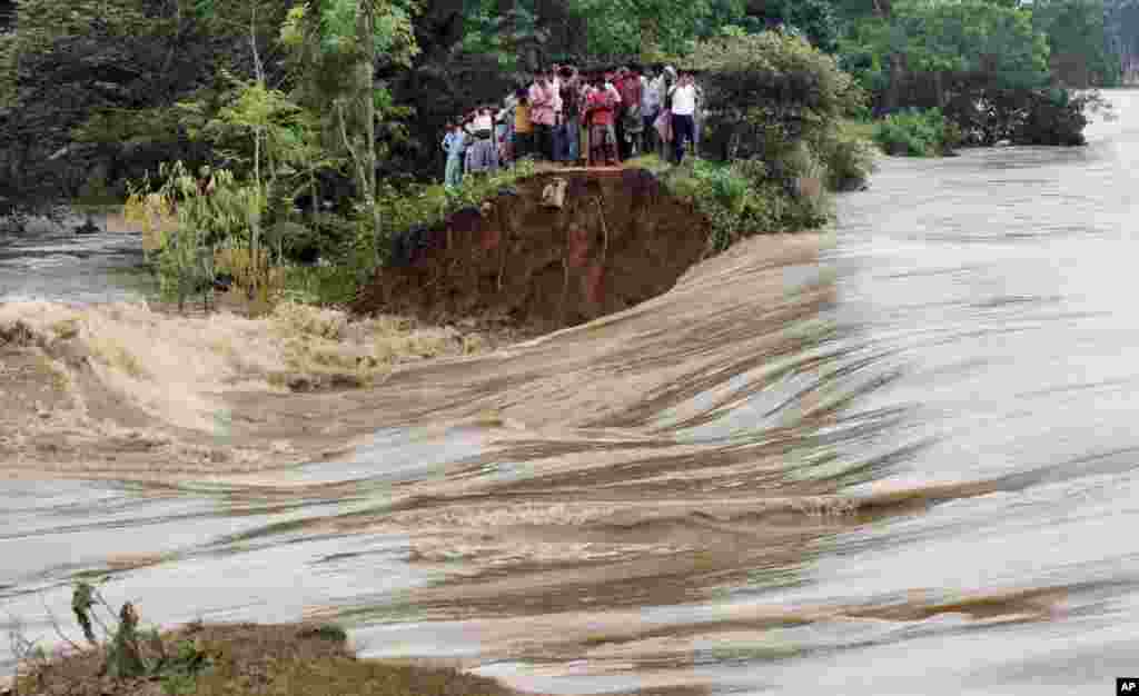 Indian villagers stand on the breached embankment of swollen Kangsabati river at Samat village in West Bengal state. Heavy torrential rain in the aftermath of weakened Cyclone Phailin have made rivers to overflow in the state.