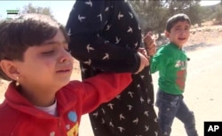 This frame grab from video provided by Muaz al-Shami, Syrian Revolution Network, an opposition activist media organization, shows children pulled by an adult after airstrikes killed nearly 30 people, mostly children, in the northern rebel-held village of Hass, Syria, Oct 26, 2016.