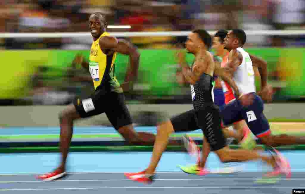 Le Jamaïcain Usain Bolt regarde le Canadien André De Grasse lors des demi-finales 100 mètres homme, à Rio de Janeiro, Brésil, le 14 août 2016.