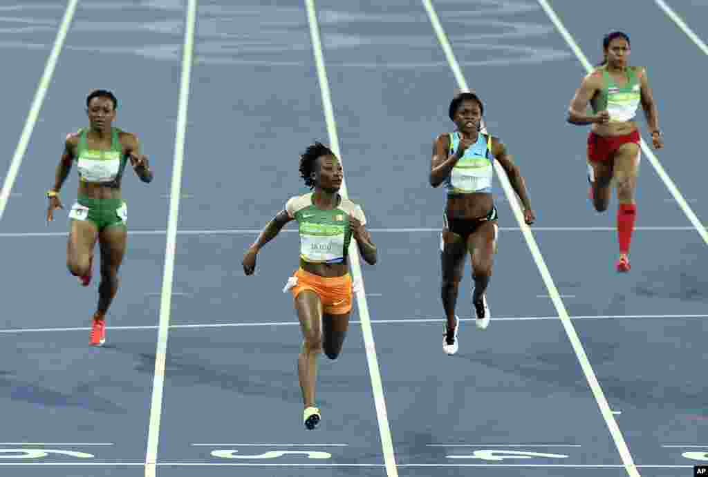 L'Ivorienne Marie-Josée Ta Lou, à l’extrême gauche, la Gabonaise Ruddy Zang Milama, deuxième à gauche, Tynia Gaither des Bahamas, deuxième à droite, et Sunayna Wahi du Surinam, à l’extrême droite, disputent une course de 100 mètres-dames aux Jeux Olympiques 2016, Brésil, le 12 août 2016.