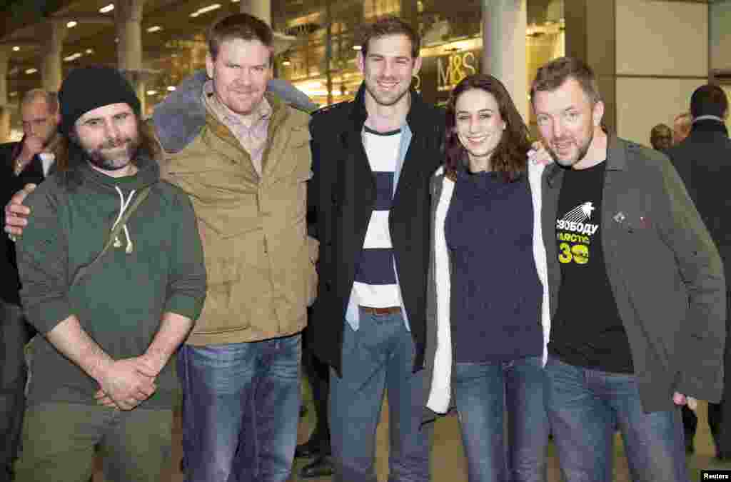 Greenpeace activists Iain Rogers (L), Anthony Perrett (2nd L), Alexandra Harris (2nd R), Phillip Ball (R) and video cameraman Kieron Bryan (C) pose for photographers after arriving at St. Pancras station in central London, England, Dec. 27, 2013. 