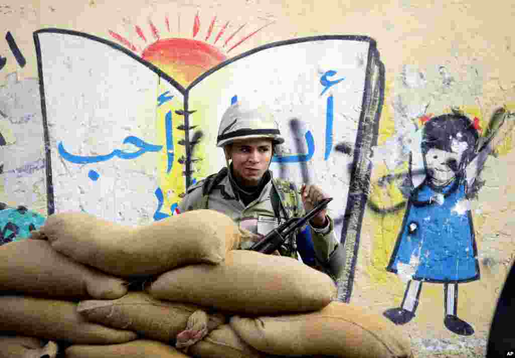 Seorang tentara berdiri di belakang barikade di sebuah TPS di Kairo (14/1). (AP/Amr Nabil)