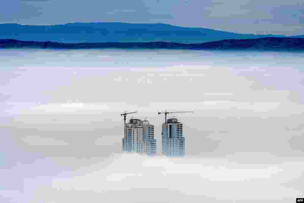 A picture taken from Vodno Mountain shows the tops of some of the city's highest buildings above clouds in an area with a high level of air pollution in Skopje, Macedonia. 