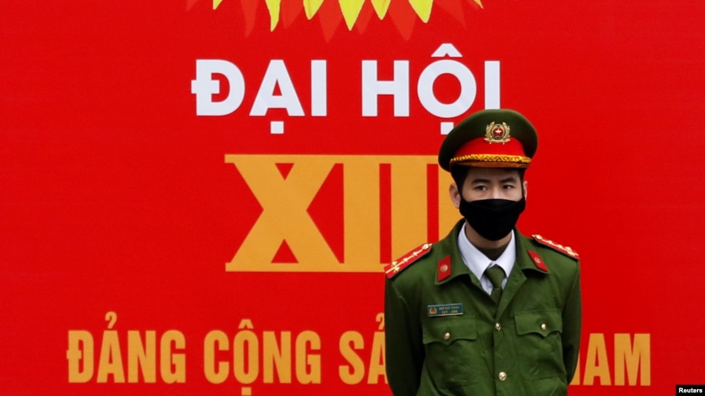A police officer stands guard in front of a poster for the upcoming 13th national congress of the Communist Party of Vietnam on a street in Hanoi, Vietnam January 20, 2021. REUTERS/Kham