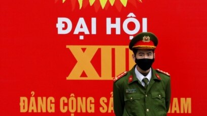 A police officer stands guard in front of a poster for the upcoming 13th national congress of the Communist Party of Vietnam on a street in Hanoi, Vietnam January 20, 2021. REUTERS/Kham