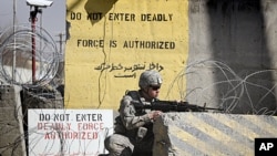A US soldier controls the area outside the gate of a US base, April 2, 2011 (file photos).