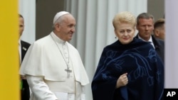 Pope Francis smiles as he arrives with Lithuanian President Dalia Grybauskaite, right, ahead of a meeting with officials, civil society and diplomatic corps in the square in front of the Presidential Palace, in Vilnius, Lithuania, Sept. 22, 2018.