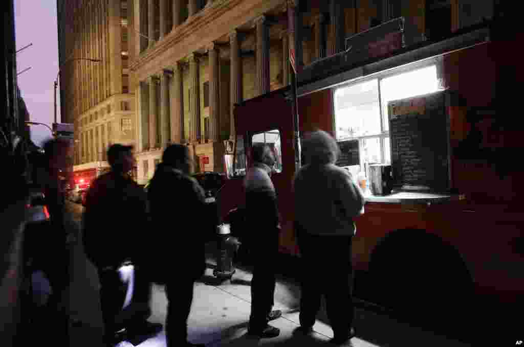 紐約市的華爾街證券交易所在桑迪颶風的侵襲下關閉兩天之後，準備在2012年10月31日星期三開市。路人在街道旁的小攤排隊買咖啡。