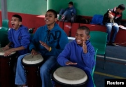FILE - From left, students Joao Farias Alves, 11, Antonio Marques, 16, and Joao Pedro dos Santos Teixeira, 11, play bongos during their music class at the Madre Lucie Bray Municipal School for the Deaf in Sao Paulo, Sept. 4, 2012. The technique of teaching music to deaf children was developed by Fabio Bonvenuto while working in this public school in 2005, where the percussionists feel the music through vibrations rather than sound waves.