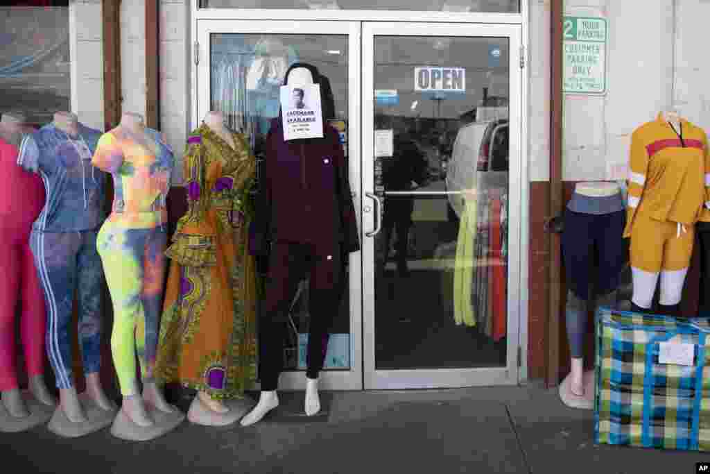 A sign that reads &quot;FACEMASK AVAILABLE&quot; is taped to a mannequin outside Trade Linker International at Union Market in Washington, D.C., March, 17, 2020.
