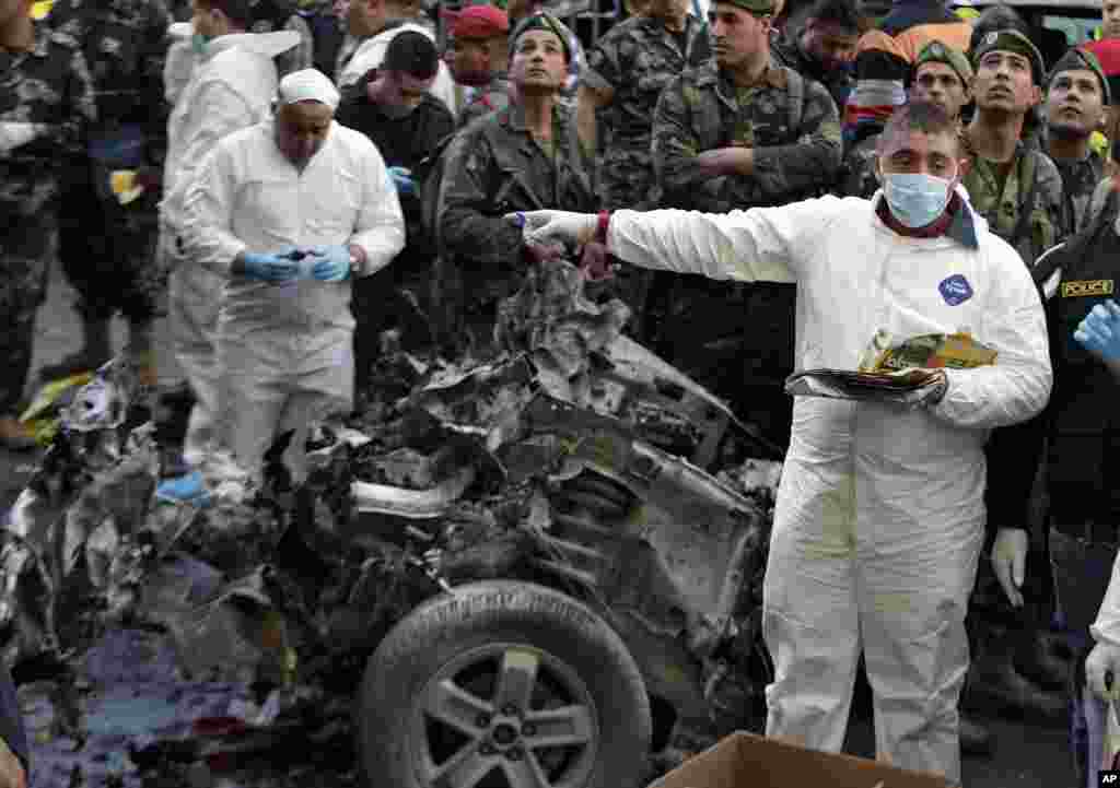 Investigators inspect parts of a destroyed car at the site of a car bombing in Beirut, Jan. 21, 2014.
