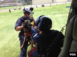 A search-and-rescue dog and its trainer are hoisted up to a helicopter as part of their training at the U.S. Park Police Aviation Section in Washington, July 11, 2015. (Credit: Julie Taboh)