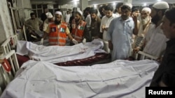 Police and hospital staff stand next to bodies of victims of a bomb attack, at the Lady Reading Hospital in Peshawar, August 31, 2012. 