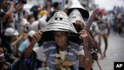 FILE - Wearing their traditional warrior helmets and jewelry, Tao aboriginal elders arrive at a traditional fishing boat launching ceremony in a village on Orchid Island, Taiwan.