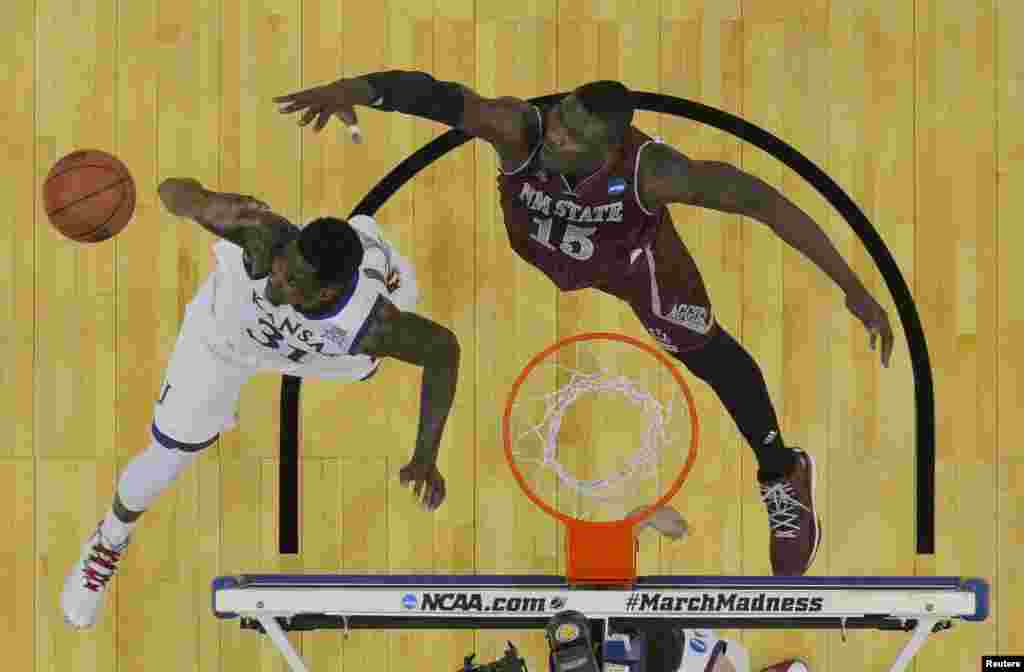 Penyerang dari tim&nbsp;​Kansas Jayhawks Jamari Traylor (nomor jersey 31) dan pemain tengah&nbsp;​New Mexico State Aggies Tshilidzi Nephawe (nomor jersey 15) berebut bola pada babak pertama putaran kedua Turnamen NCAA 2015 di CenturyLink Center, di Omaha, Nebraska. (Jasen Vinlove-USA TODAY Sports)&nbsp;