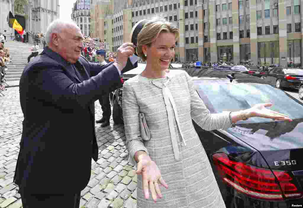 Vice-Admiral Pierre Warnauts, head of protocol of the Household of His Majesty the King, adjusts the hat of Queen Mathilde of Belgium after a mass commemorating the 20th anniversary of King Baudouin&#39;s death at Saint Gudule cathedral in Brussels.