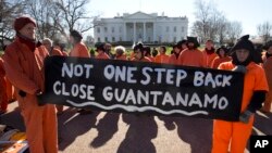 Demonstran yang mengenakan pakaian seperti tahanan penjara Guantanamo memegang poster bertuliskan tuntutan penutupan Guantanamo di Kuba saat berunjuk rasa di Gedung Putih di Washington, 11 Januari 2016.