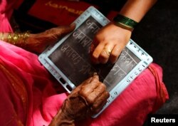 Sheetal Prakash More (R), a 30-year-old teacher, helps Janabai Kedar, 74, as she writes on a slate at Aajibaichi Shaala (Grandmothers' School) in Fangane village, India, Feb. 15, 2017.