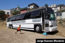 A migrant child runs towards a bus converted in a classroom as part of Schools On Wheels program by California's 'Yes We Can' organization, in Tijuana, Mexico August 2, 2019