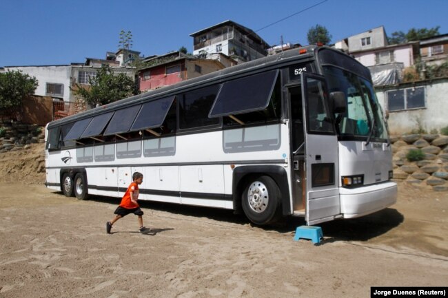 A migrant child runs towards a bus converted in a classroom as part of Schools On Wheels program by California's 'Yes We Can' organization, in Tijuana, Mexico August 2, 2019