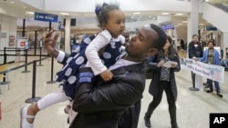 Abdisellam Hassen Ahmed, pengungsi Somalia yang nasibnya sempat tidak jelas menyusul instruksi Presiden AS Donald Trump, menggendong putrinya setelah bertemu lagi di Bandar Udara Internasional Salt Lake City, Utah (10/2). (AP/Rick Bowmer)