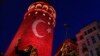 People take photos at the iconic Galata Tower, illuminated in Turkish flag colors, in Istanbul, July 30, 2016. Some signals from President Recep Tayyip Erdogan's administration show no letup in reprisals following an abortive coup attempt two weeks ago.