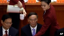 Vice Premier Wang Qishan, center, is served a drink by a hostess during the opening session of the 18th Communist Party Congress at the Great Hall of the People in Beijing, Nov. 8, 2012