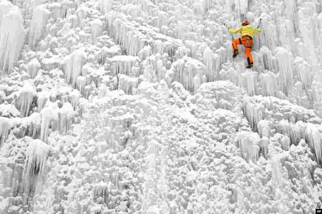 A man climbs up an artificial ice wall located in a courtyard in the city of Liberec, Czech Republic.