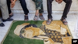 Libyan rebels use a carpet with the image of Moammar Gadhafi as a doormat at their camp, set up in a district of Gadhafi sympathizers in the stronghold city of Tarhouna, 100 kilometers southeast of Tripoli, Libya, August 29, 2011