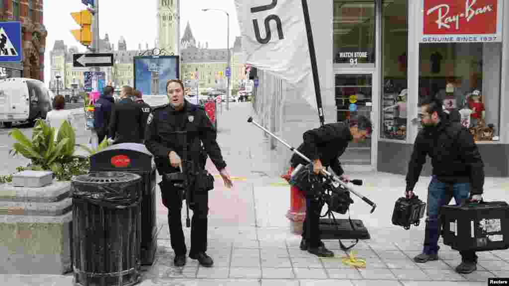 Un officier de police d&#39;Ottawa en train de disperser des journalistes près du lieu de la fusillade, sur la rue&nbsp; Metcalfe après une attaque meurtrière à Ottawa, le 22 octobre 2014. 