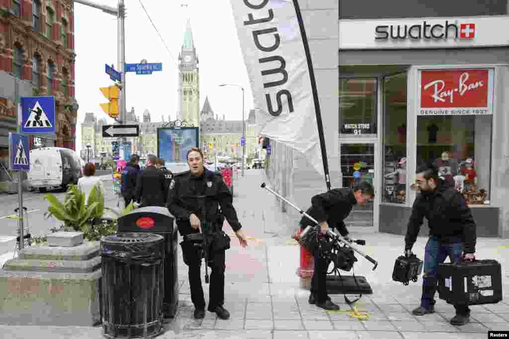 An Ottawa police officer attempts to clear people from an area on Metcalfe Street following shootings in downtown Ottawa.
